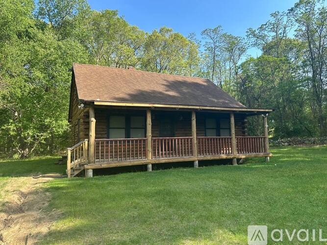 A wooden house with a porch is surrounded by trees.