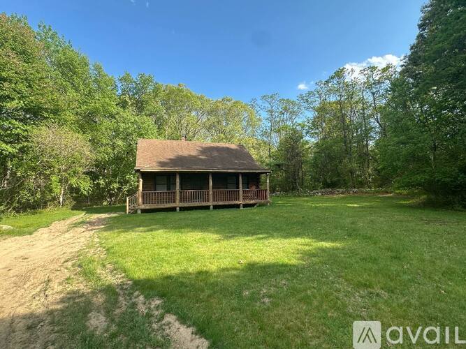 A house with a porch is surrounded by trees and grass.