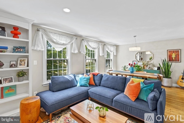 A bright living room with a blue couch and a wooden coffee table.