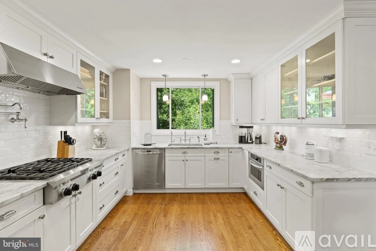 A modern kitchen with white cabinets and a wooden floor.