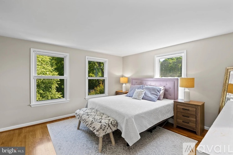A bedroom with a large bed, two windows, and a nightstand.
