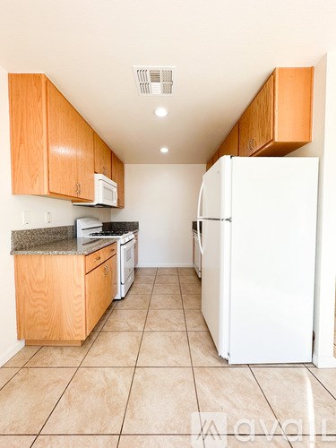 A kitchen with a white refrigerator and wooden cabinets.