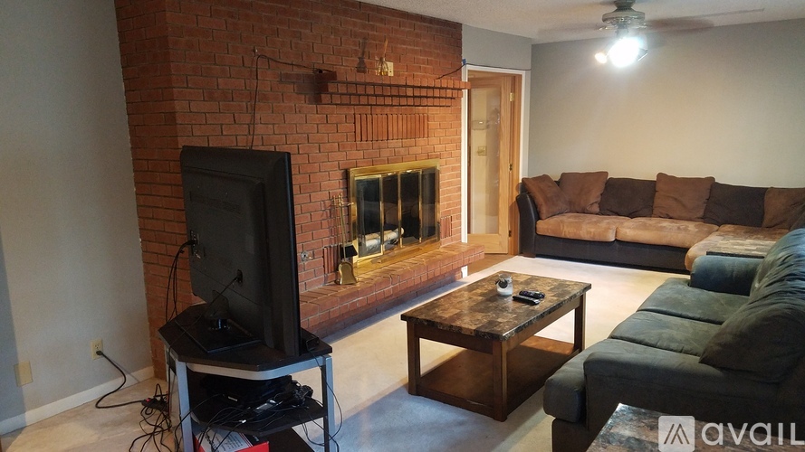 A living room with a brick fireplace and a television on a stand.