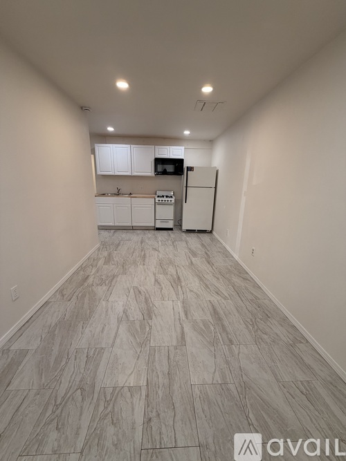 A kitchen with white cabinets and a refrigerator is available for rent.