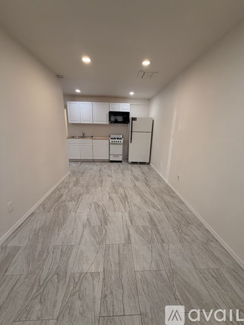 A kitchen with white cabinets and a refrigerator is available for rent.