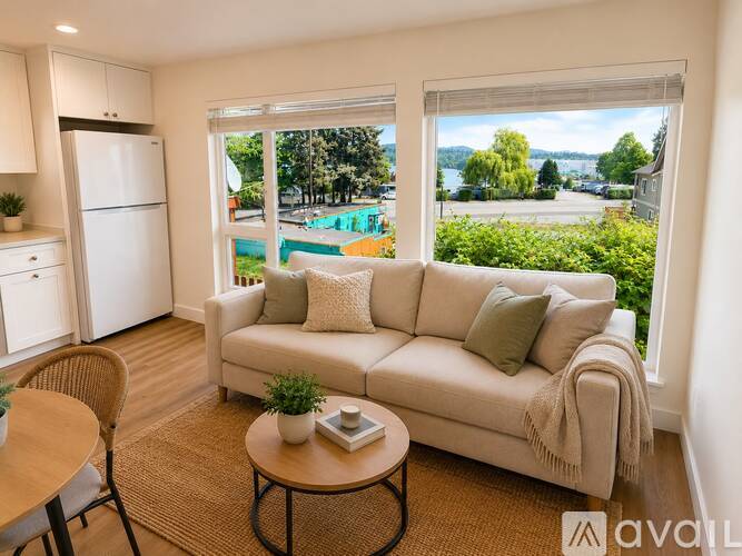 A living room with a couch, a table, and a window overlooking a pool.