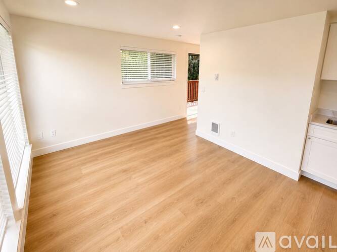 A spacious room with wooden flooring and white walls.
