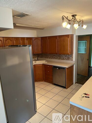 A kitchen with a refrigerator, cabinets, and a counter.