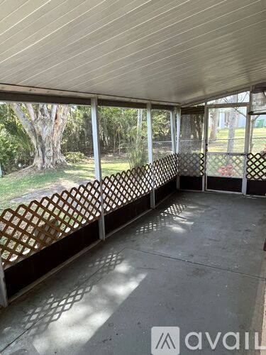 A patio with a lattice fence and a view of trees and a lawn.