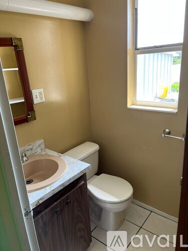 A bathroom with a toilet, sink, and mirror.