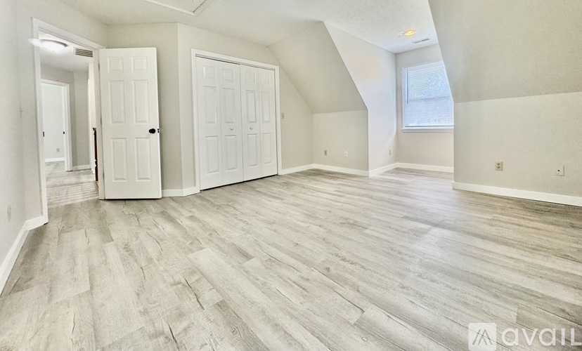 A spacious room with wood flooring and white walls.