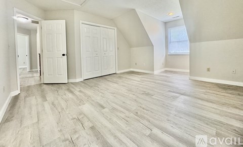 A spacious room with wood flooring and white walls.