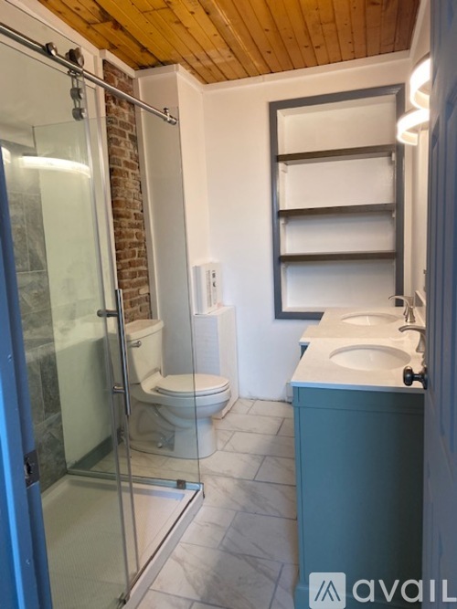 A bathroom with a glass shower door and a toilet.