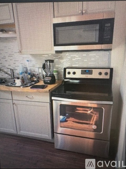A modern kitchen with a stainless steel oven and white cabinets.