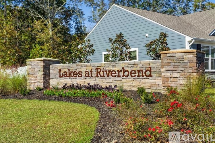 A sign that says Lakes at Riverbend in front of a house.