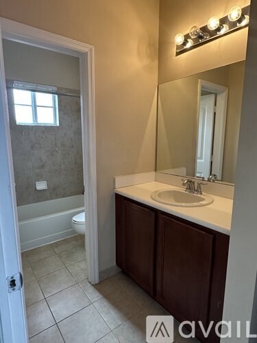 A bathroom with a white sink and brown cabinets.