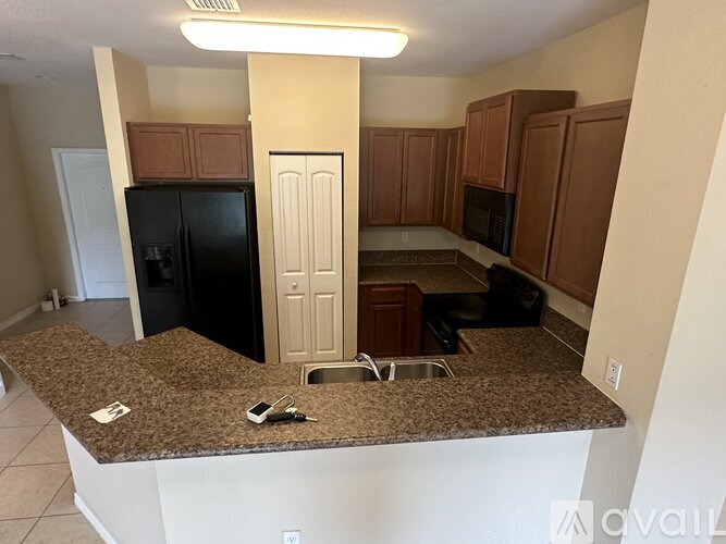 A kitchen with brown cabinets and a black refrigerator.