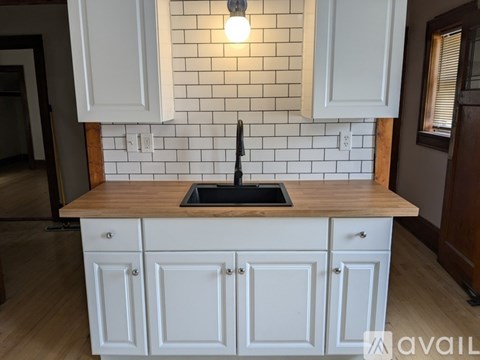 A kitchen with white cabinets and a wooden countertop.
