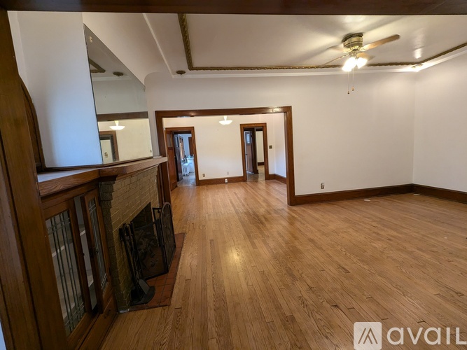 A spacious room with wooden floors and a fireplace.