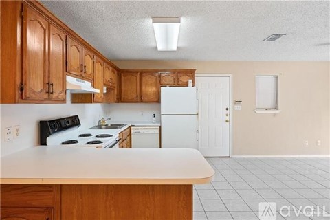 A kitchen with wooden cabinets and a white stove top oven.
