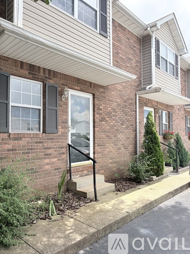 A brick house with a window and a small tree in front.