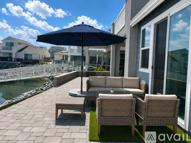 A patio with a table, chairs, and an umbrella overlooking a pool.