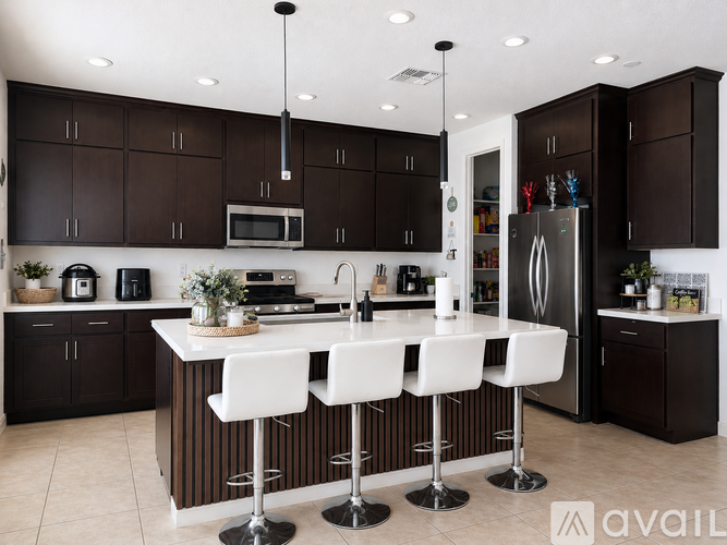 A modern kitchen with dark brown cabinets and white countertops.