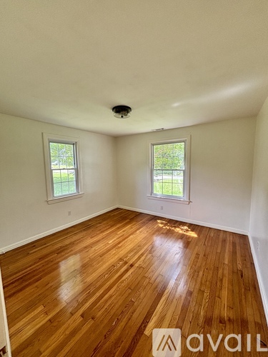 A room with wooden floors and two windows.