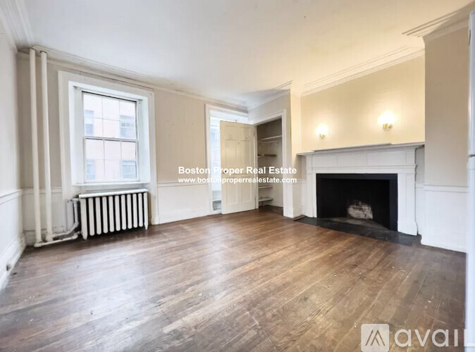 A large, empty room with wooden floors and a fireplace.