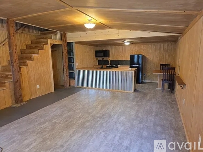 A spacious room with wooden walls and a staircase on the left side.