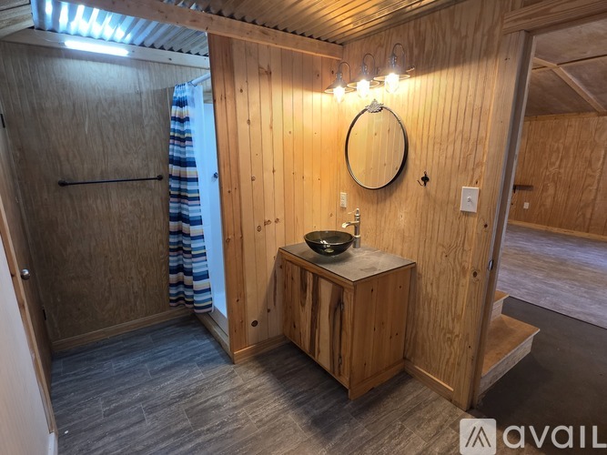 A wooden bathroom with a round mirror and a bowl on a counter.