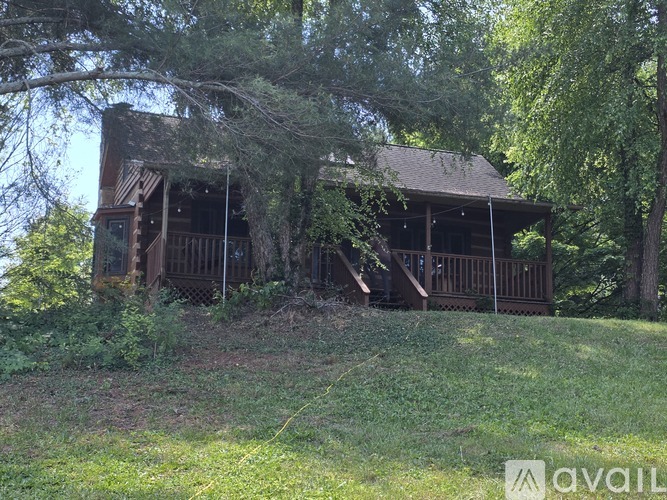 A wooden cabin is surrounded by trees and grass.