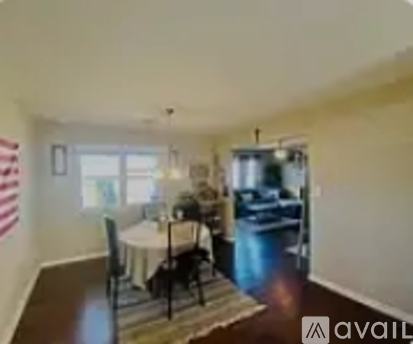 A dining room with a table set for two and a kitchen in the background.