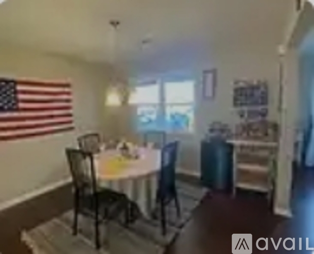 A dining room with a table and chairs and an American flag hanging on the wall.