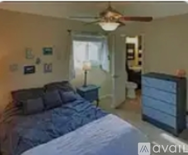 A bedroom with a bed, a ceiling fan, and a nightstand.