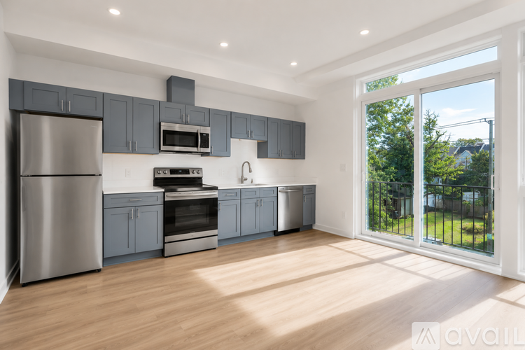 A modern kitchen with stainless steel appliances and wooden flooring.