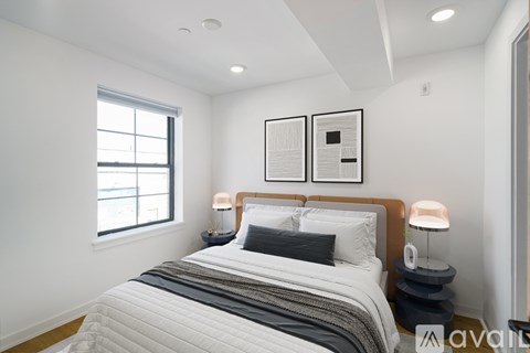 A bedroom with a large bed, two lamps, and two framed pictures on the wall.
