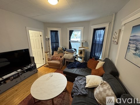 A living room with a grey couch, a white coffee table, and a television.