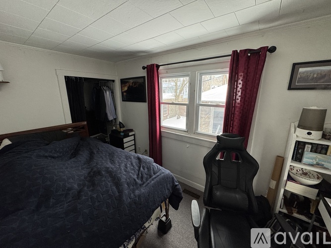 A bedroom with a bed, chair, and window.