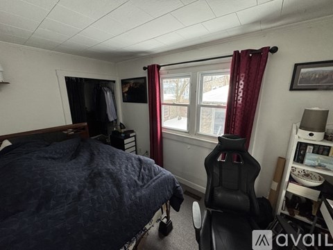 A bedroom with a bed, chair, and window.