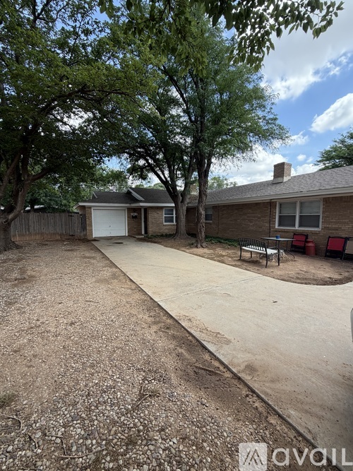 A backyard with a tree, a bench, and a house.