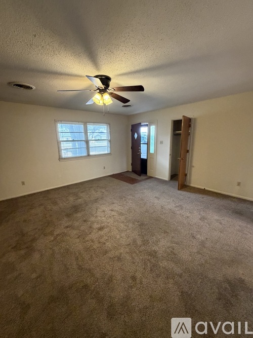 A room with a ceiling fan and carpeted floor.