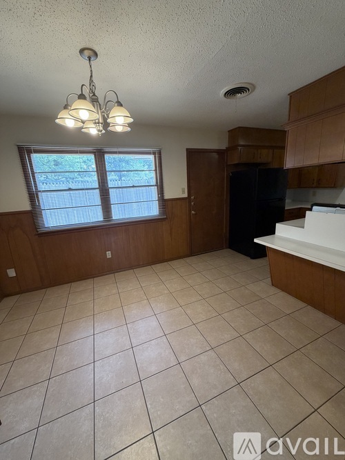 A kitchen with wooden cabinets and a black refrigerator.