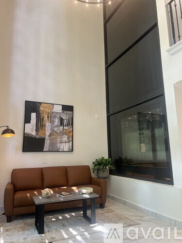 A brown couch sits in front of a framed picture in a living room.