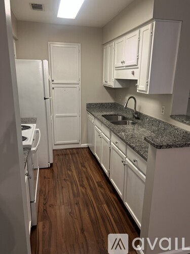 A kitchen with white cabinets and a granite countertop.