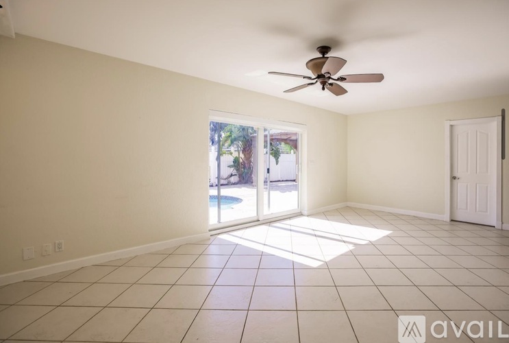 A room with a ceiling fan and sliding glass doors leading to a pool area.