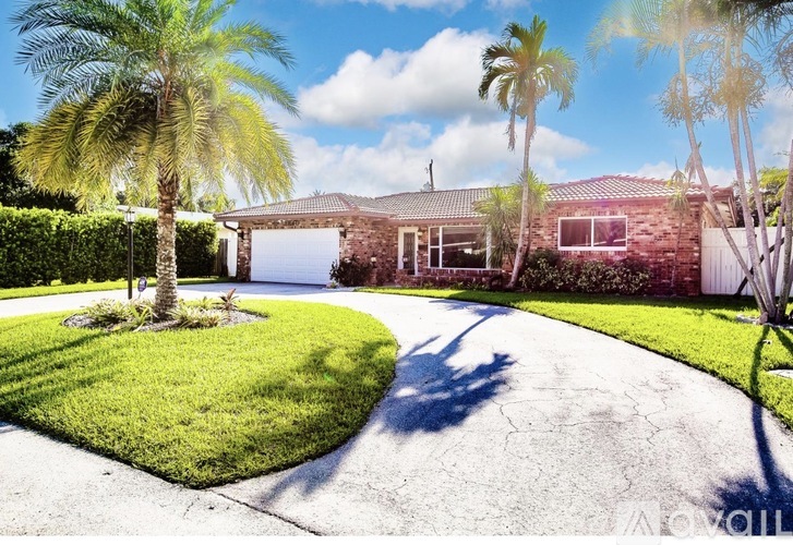 A house with a driveway and palm trees in front.