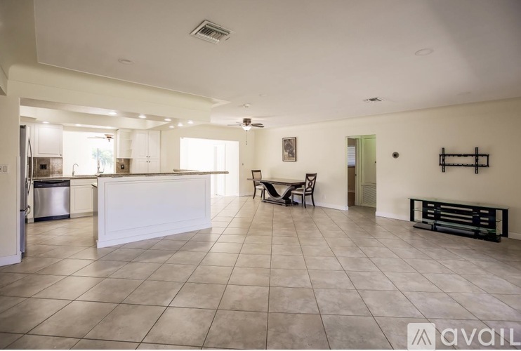 A spacious kitchen with a white counter and a tiled floor.