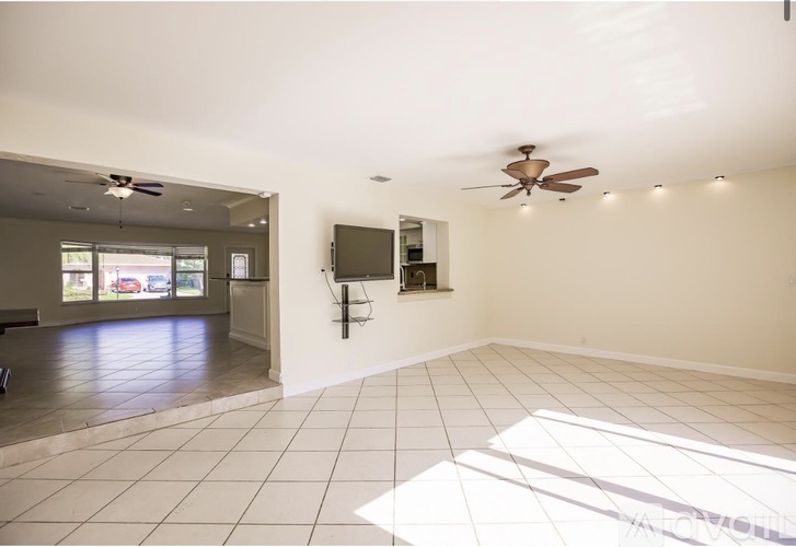 A spacious room with a ceiling fan and a flat screen TV mounted on the wall.