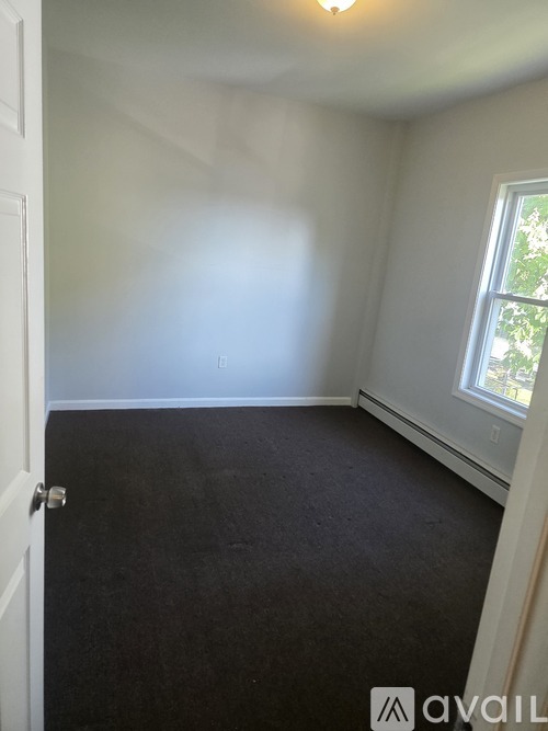A room with a carpeted floor and a window.